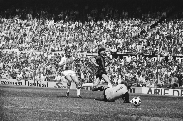 Schwarzes und weißes Foto von Männern, die auf einem Feld Fußball spielen, mit Zuschauern im Hintergrund und einem Banner mit der Aufschrift "Bundesliga 1978-79 Ajax 1:1 Hannover 96."