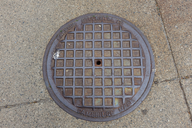Ein rundes Metallgullideckel auf einem Stadtweg mit eingravierter Schrift.
