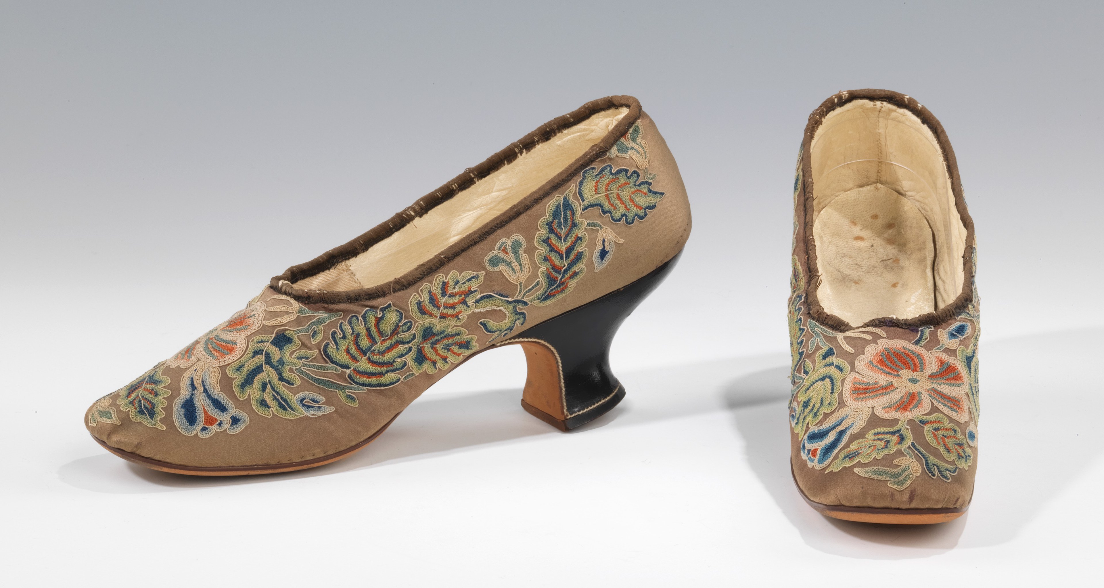 Ein Paar Frauen-Schnürschuhe mit Stickerei und spitzer Zehe, niedriger Absatz und farbenfrohen floralen Mustern in Blau, Grün und Gelb auf weißem Hintergrund.