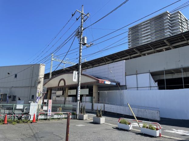 Großes Gebäude mit zahlreichen Stromleitungen davor, umgeben von städtischer Infrastruktur unter einem klaren blauen Himmel.