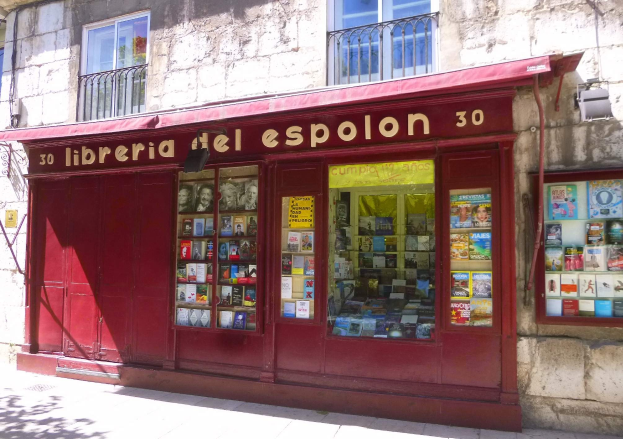 Eine gut sortierte Buchhandlung namens "Libreria del Espolon" mit einer roten Markise, die Bücher ordentlich in Regalen zeigt.