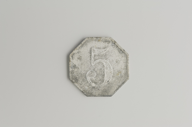 Eine Fünf-Cent-Münze mit der Zahl fünf auf einer weißen Oberfläche.