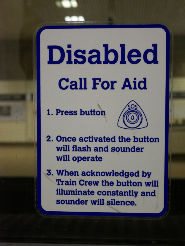 Eine Glastür mit einem sichtbaren "Behinderten-Notruf"-Schild daran befestigt.