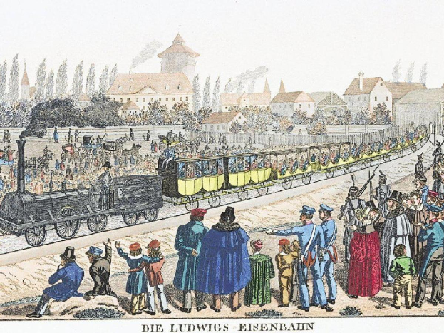 Eine Gruppe von Menschen steht in der Nähe eines Zuges auf den Schienen, einige sitzen im Zug und andere auf dem Boden, vor einem Hintergrund aus Gebäuden und Bäumen, mit dem Text "Ludwigs-Eisenbahn, die erste Bahnstation in Deutschland" unten.
