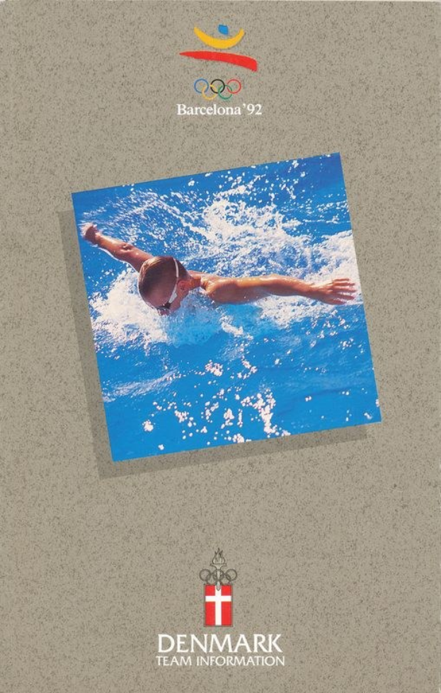 Plakat eines Schwimmers in blauer Badehose mit ausgebreiteten Armen im Wasser, mit dem Logo und Text der Olympischen Spiele 1992 in Barcelona und "Denmark Team Information" gegen einen hellblauen Himmel mit weißen Wolken.