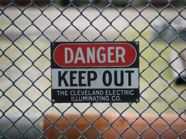 Ein rotes Gefahrenzeichen an einem Kettenzaun mit der Aufschrift "Zutritt verboten" und einem unscharfen Hintergrund.