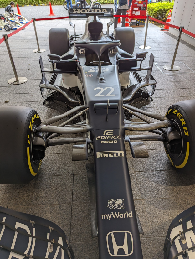Ein McLaren Mercedes MP4-23 Formel-Eins-Rennwagen bei der Singapore Grand Prix, umgeben von Barrieren, Verkehrskegeln, Menschen, Fahrzeugen, Pflanzen, Bäumen und einem Gebäude im Hintergrund.