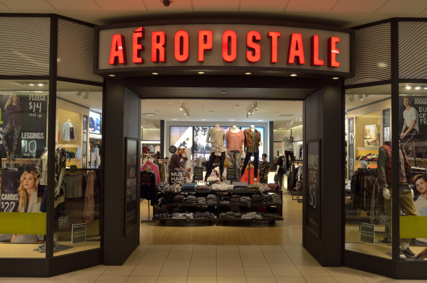 Aeropostale-Laden im Einkaufszentrum mit Schaufensterpuppen in Kleidern, Kleiderständern, Informationsschildern, Glaswänden und Beleuchtung, mit Hinweisen auf die Schließung im Juni.