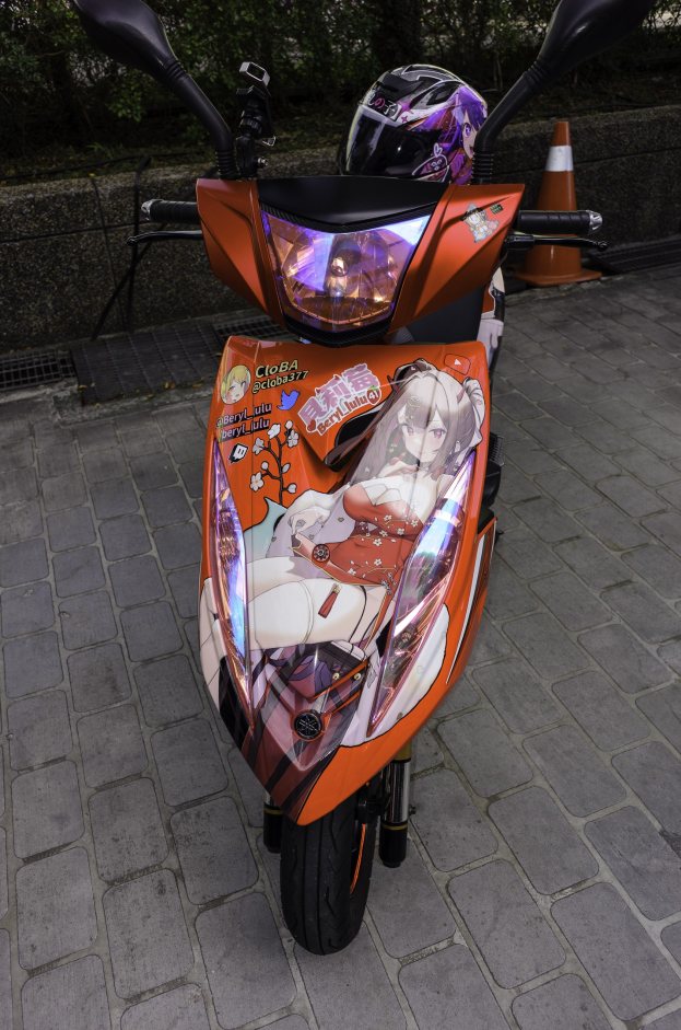 Ein oranges Roller-Fahrzeug mit einem Helm darauf auf einer Straße geparkt, mit einem Verkehrskegel, einer Wand und Bäumen im Hintergrund.