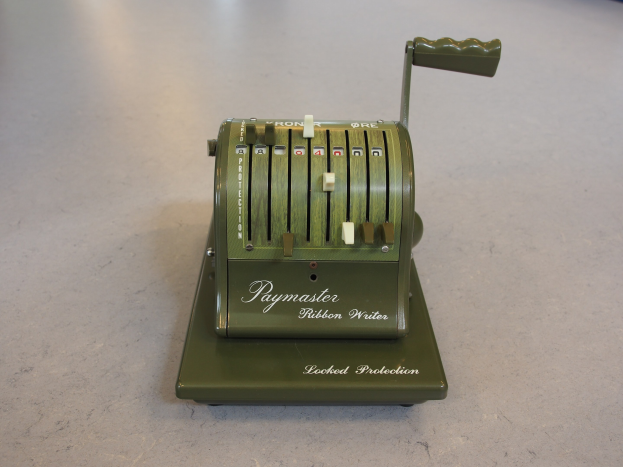 Alte grüne Kasse auf einem Zementboden mit ein paar Gegenständen im Hintergrund.