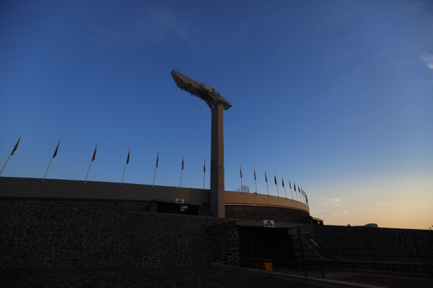 Olympiastadion in Rio de Janeiro mit zentralem Pfahl, umgeben von einer Wand und einigen Fahnen im Himmel.