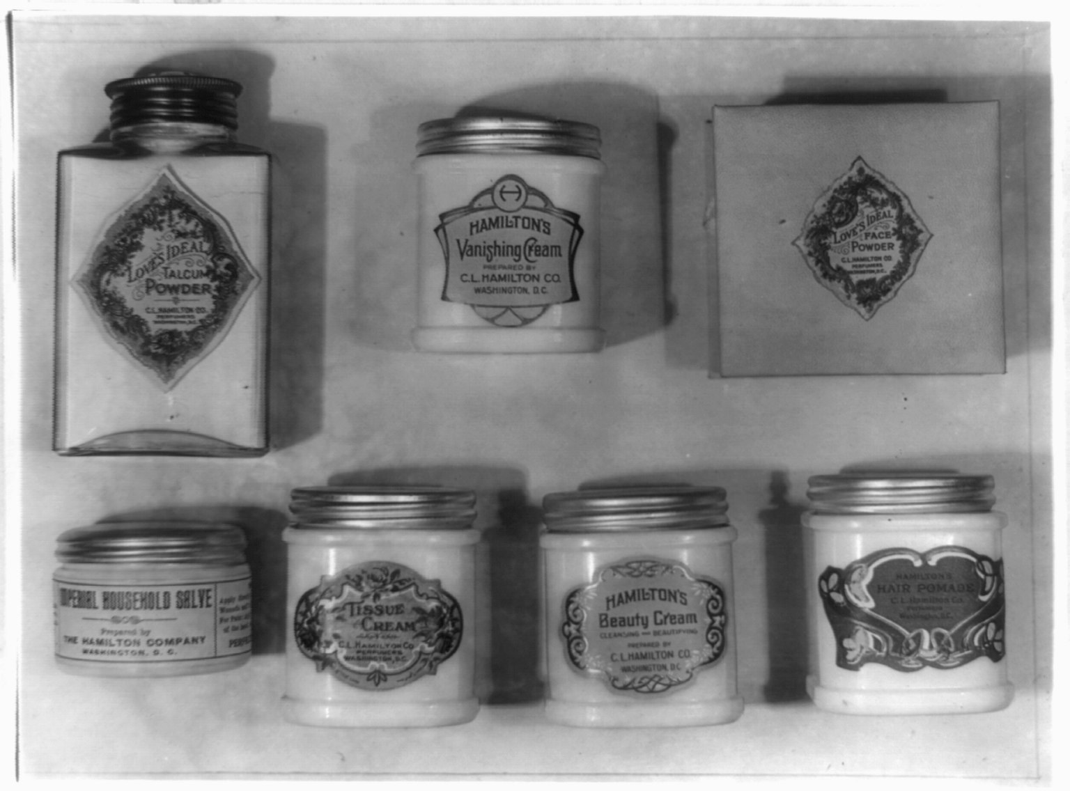 Schwarz-weiß-Foto eines Regals mit ordentlich angeordneten Cremetöpfen.