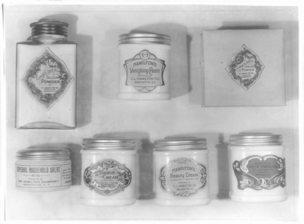 Schwarz-weiß-Foto eines Regals mit ordentlich angeordneten Cremetöpfen.