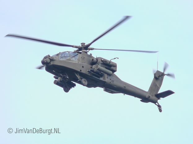 Ein militärischer Chinook-Hubschrauber fliegt mit ausgefahrenem Fahrwerk, seine beiden Rotoren drehen sich schnell gegen einen klaren Himmel.