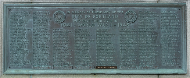 Metallplatte an einer Gebäudewand angebracht, mit der Aufschrift "Denkmal für die Stadt Portland" in fetter schwarzer Schrift und einem dekorativen Rahmen.