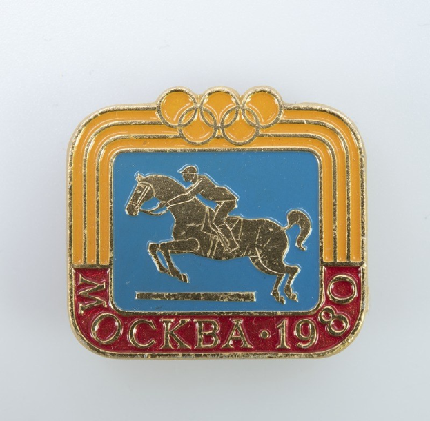 Olympisches Abzeichen der Winterspiele 1988 mit einer braunen Stute mit weißer Mähne und Schweif, geritten von einer Person in einem weißen Hemd und blauen Shorts, vor einem hellblauen Himmel mit weißen Wolken.