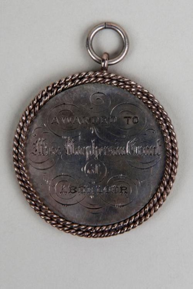 Silberne Medaille mit schwarzem Text "Ausgezeichnet an den Metropolitan Council" auf einem dekorativen Rand, an einem Seil hängend.