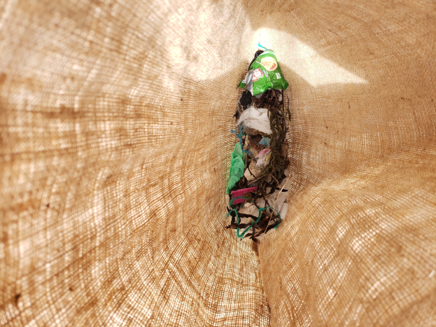 Nahaufnahme eines zerknüllten Papierstücks auf einem Tisch mit einem Jutestoff im Hintergrund, wahrscheinlich recyceltes Abfallmaterial.